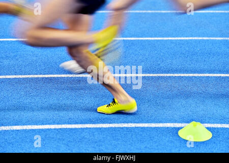 Blurred athletes by a slow camera shutter speed competing on blue sprint track Stock Photo