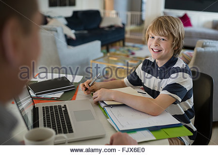 Son doing homework smiling at father