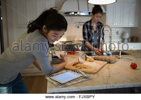 Woman using digital tablet cooking recipe in kitchen