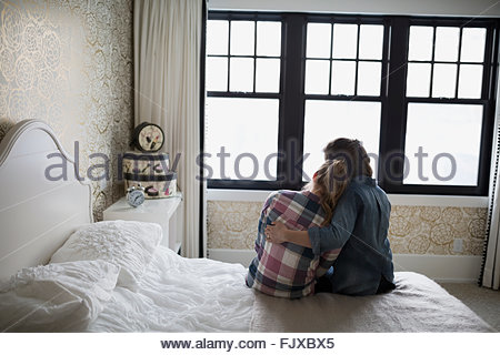 Mother hugging teenage daughter in bedroom