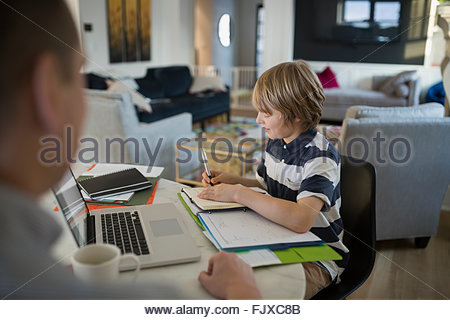 Father watching son doing homework at kitchen table