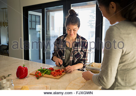 Mother and teenage daughter slicing vegetables in kitchen