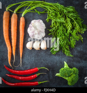Hot chilli peppers, Dutch sweet carrots, broccoli, and garlic creatively arranged on grunge background. Top view. Stock Photo