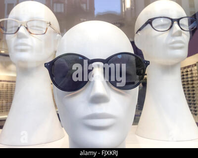 Three mannequin heads in shop window with urban reflections Stock Photo