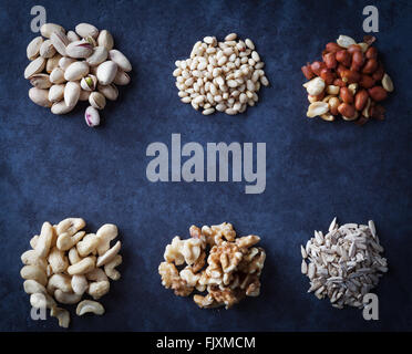 Pistachios, pine nuts, peanuts, cashews, walnuts and sesame seeds on grunge background. Flat lay. Stock Photo