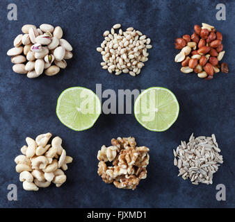 Pistachios, pine nuts, peanuts, cashews, walnuts, lime, and sesame seeds on grunge background. Flat lay. Stock Photo