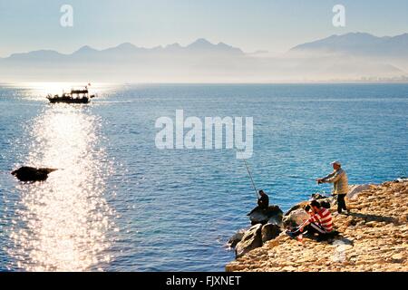 Antalya, Turkey. Looking west from entrance of Kaleici harbour.  Fishermen and tourist sightseeing boat Stock Photo