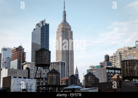 View of many old wooden water towers on top of high buildings in New York city with Empire state building in background
