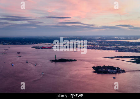 Aerial view from Manhattan showing Ellis Island, the statue of liberty, port liberty in New Jersey with pink sunset reflections Stock Photo