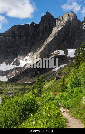 Hiking on Iceberg Lake Trail amoung huge mountain Stock Photo