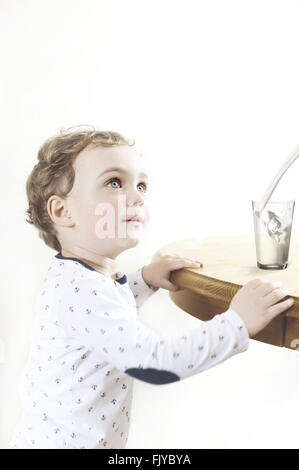small boy by the wooden table with glass of milk Stock Photo