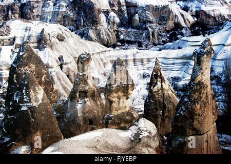 Eroded volcanic tuff rock pillars fairy chimneys hoodoos in Goreme National Park, Cappadocia, Turkey. Winter snow Stock Photo