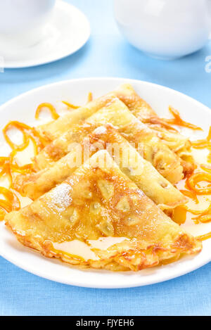 Crepes with syrup from orange on white plate Stock Photo