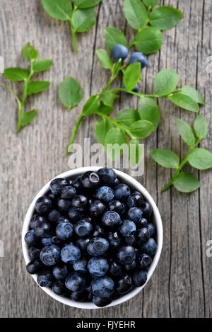 Ripe blueberries in bowl on wooden background, top view Stock Photo