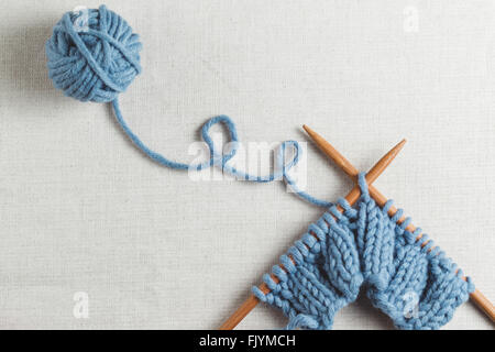 Knitted blue yarn with wooden needles Stock Photo