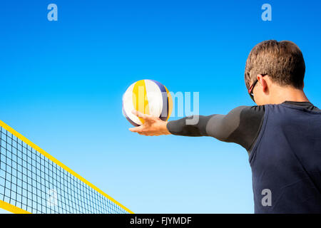 Beach volleyball player concentrates to pitch the ball over the net Stock Photo