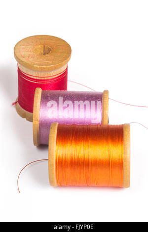 Three colorful spools of orange, purple and red nylon thread on white background Stock Photo
