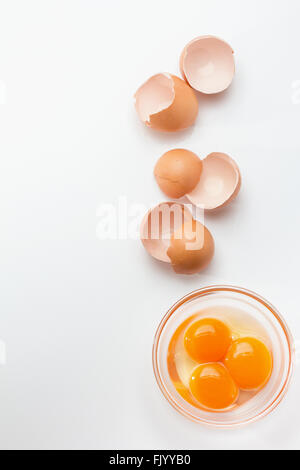Broken eggshells with egg yolks in glass bowl Stock Photo