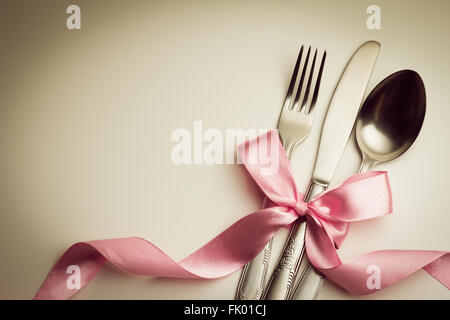 Fork, spoon and knife with decorative ribbon. Stock Photo