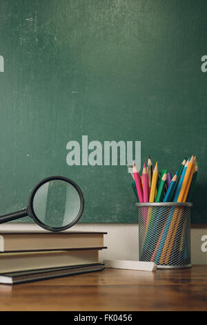 Table with pencils, magnifier and stack of books Stock Photo