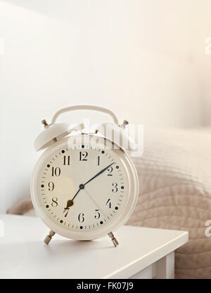 retro white alarm clock on white table in the bedroom, copy space Stock Photo