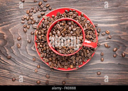 red cup filled with coffee beans on wooden background, flat lay Stock Photo