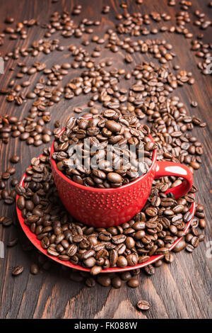 red cup filled with coffee beans on wooden background Stock Photo