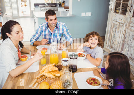 Happy family eating breakfast at table in house Stock Photo