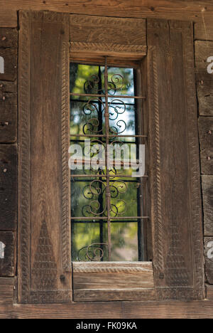 Old window with ornamented metal lattice in traditional wooden Romanian house. Dimitrie Gusti National Village Museum. Bucharest Stock Photo
