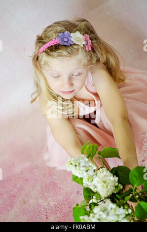 beautiful girl with long blond hair holding flowers, wearing home hand made headband Stock Photo