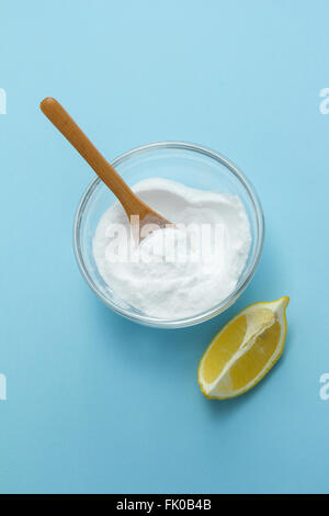 Bowl of baking soda and lemon on blue background. Natural cleaning products Stock Photo