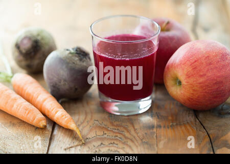 Glass of fresh beetroot, apple and carrot juice on wooden table. Stock Photo