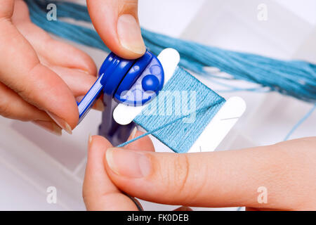 Preparations for embroidery. Woman hands reeling up thread on spool. Stock Photo
