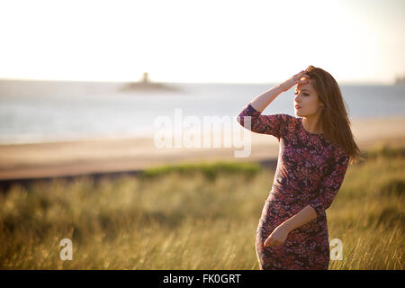 Young women in floral dress among nature, long natural green grass and Bunny Tails (Lagurus ovatus) Stock Photo