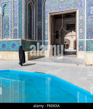 Ablutions pool and chador-clad woman at entrance to Masjed-e Jame (Friday mosque), Yazd, Iran Stock Photo