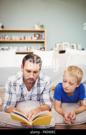 Close-up of father and son reading book while lying on floor Stock Photo