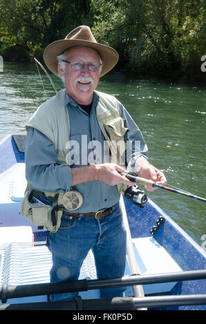 Portrait of a happy retired senior man spending time on the water fishing. Stock Photo