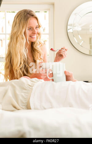 Cute couple eating cereals and lying in bed Stock Photo