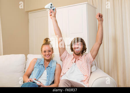 Cute couple playing video games sitting on the couch Stock Photo