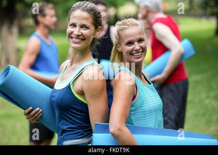 Fit women posing with sports mats back to back Stock Photo