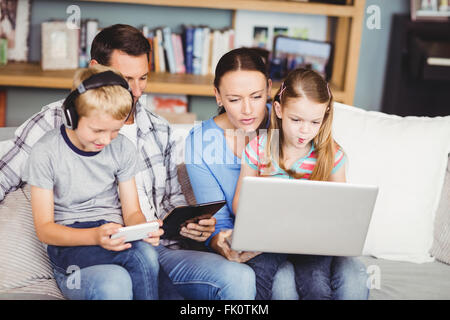 Children using technologies with parents on sofa Stock Photo