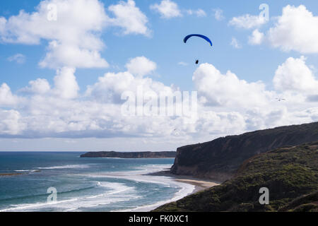 A paraglider and hang glider flying over Southside Beach, near Bell's Beach in Torquay, Victoria, Australia Stock Photo