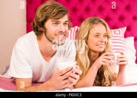 Cute couple relaxing on their bed and having coffee Stock Photo
