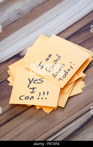 close up of small sticky notes on a wooden desk , all with different positive notes Stock Photo