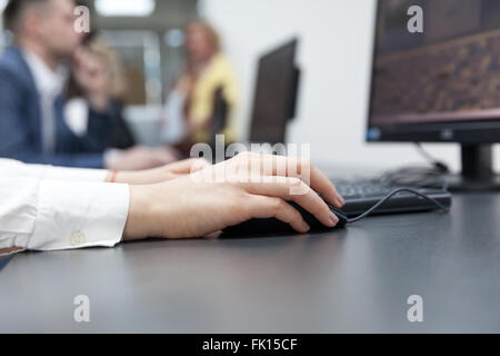 Close up of female hand on mouse while typing on keyboard Stock Photo