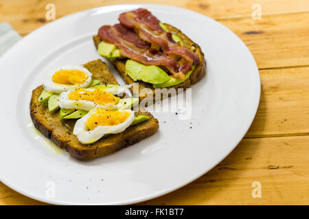 Avocado toast, bacon, egg, on a wooden table, space for text Stock Photo