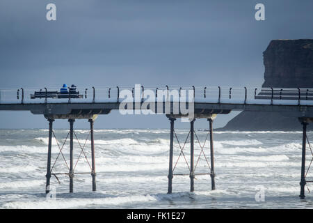 Saltburn by the sea, North Yorkshire, England, UK, 5th March 2016. Weather: A couple sitting on Saltburn`s Victorian pier as an icy wind blows in off the cold North sea. Credit:  Alan Dawson News/Alamy Live News Stock Photo