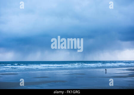 Saltburn by the sea, North Yorkshire, England, UK, 5th March 2016. Weather: A photographer on Saltburn beach at sunrise as as a curtain of rain passes and  an icy wind blows in off the cold North sea. Credit:  Alan Dawson News/Alamy Live News Stock Photo