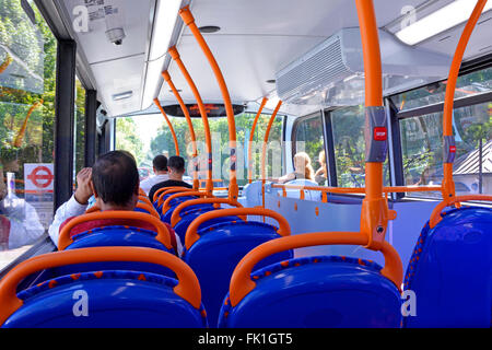 London bus interior view of passengers seated on upper deck of  double decker bus waiting at bus stop sign visible through window England UK Stock Photo