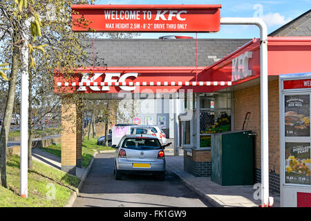 KFC fast food drive through lane with customer in car at ordering window handing back credit card charging pad obscured number plate